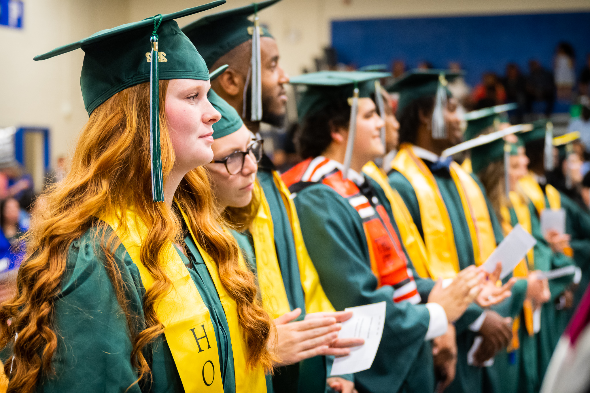 Graduates standing in row waiting to line up to receive diploma