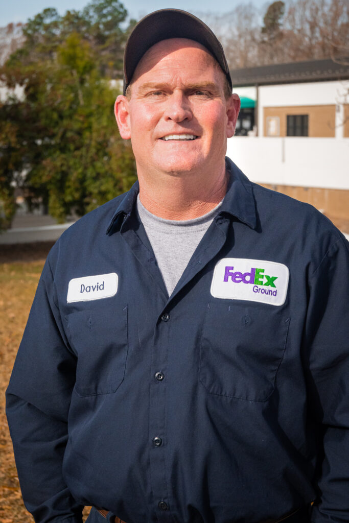 Man in FedEx uniform standing in front of building during sunset