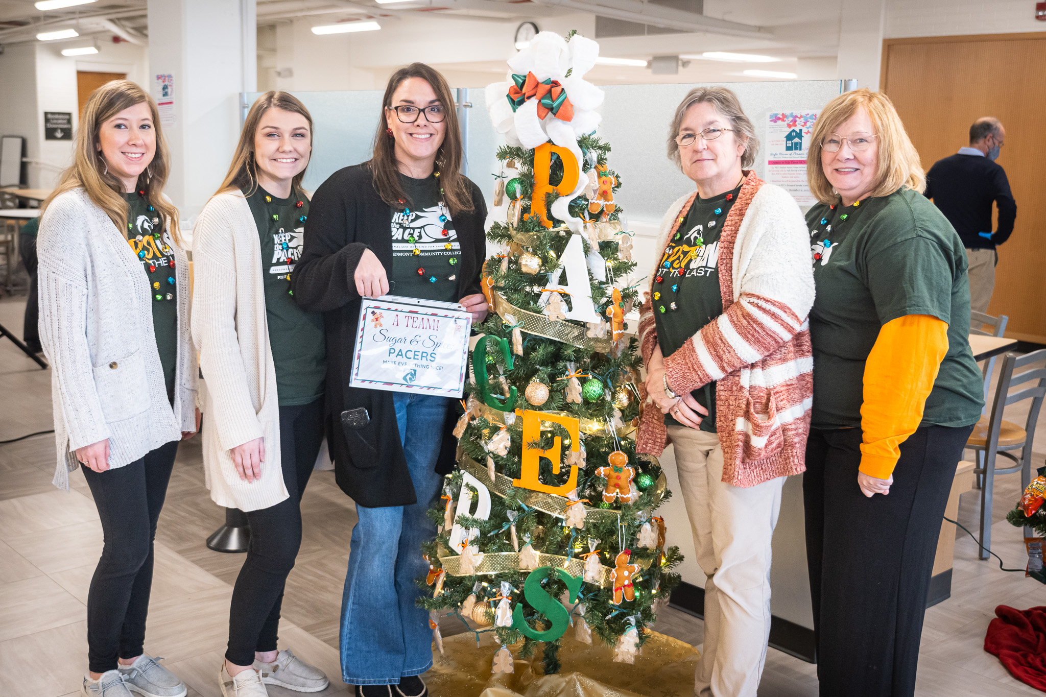 Five women standing next to a PCC Pacer themed Christmas tree